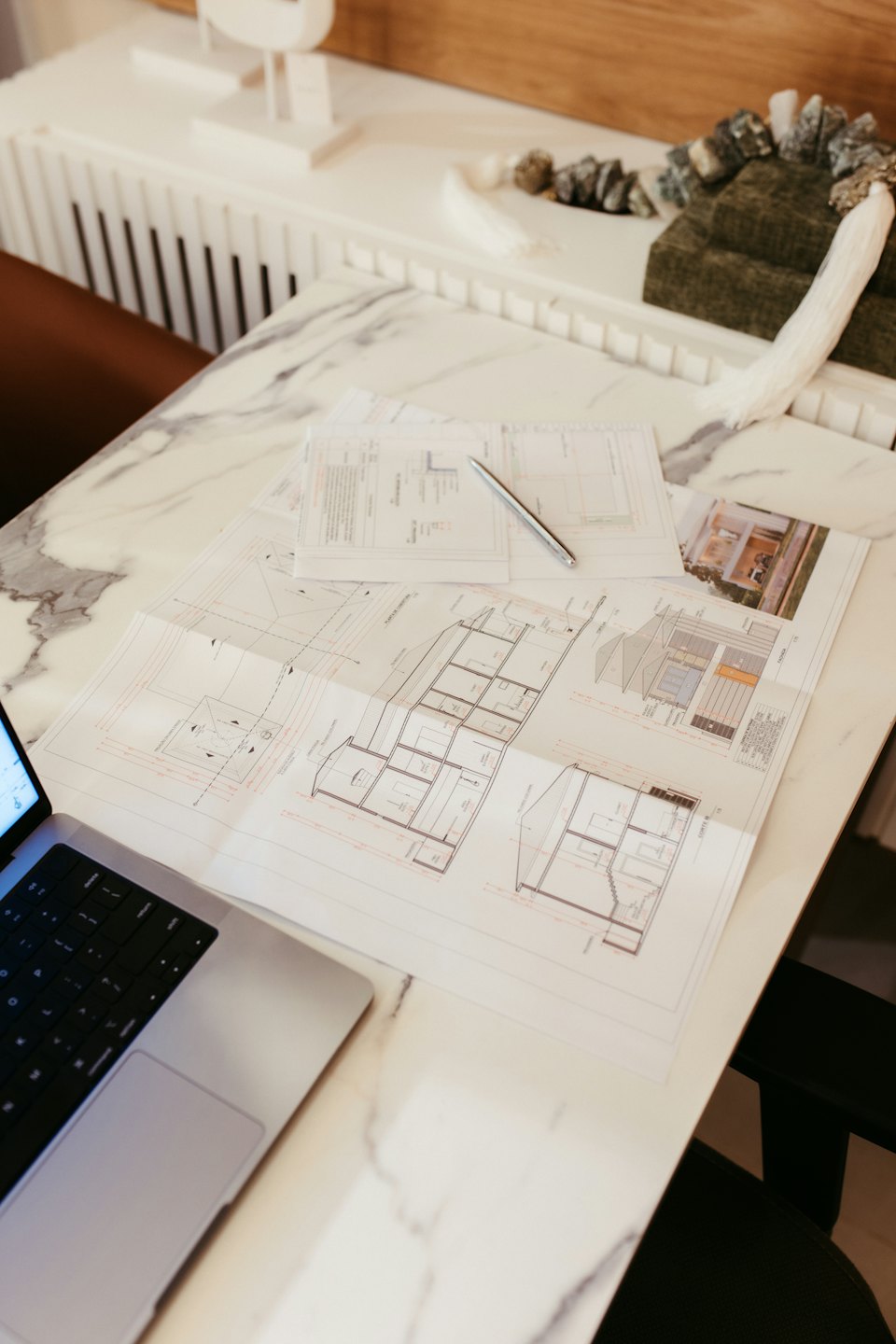 Progetti architettonici e computer portatile su un tavolo di marmo.