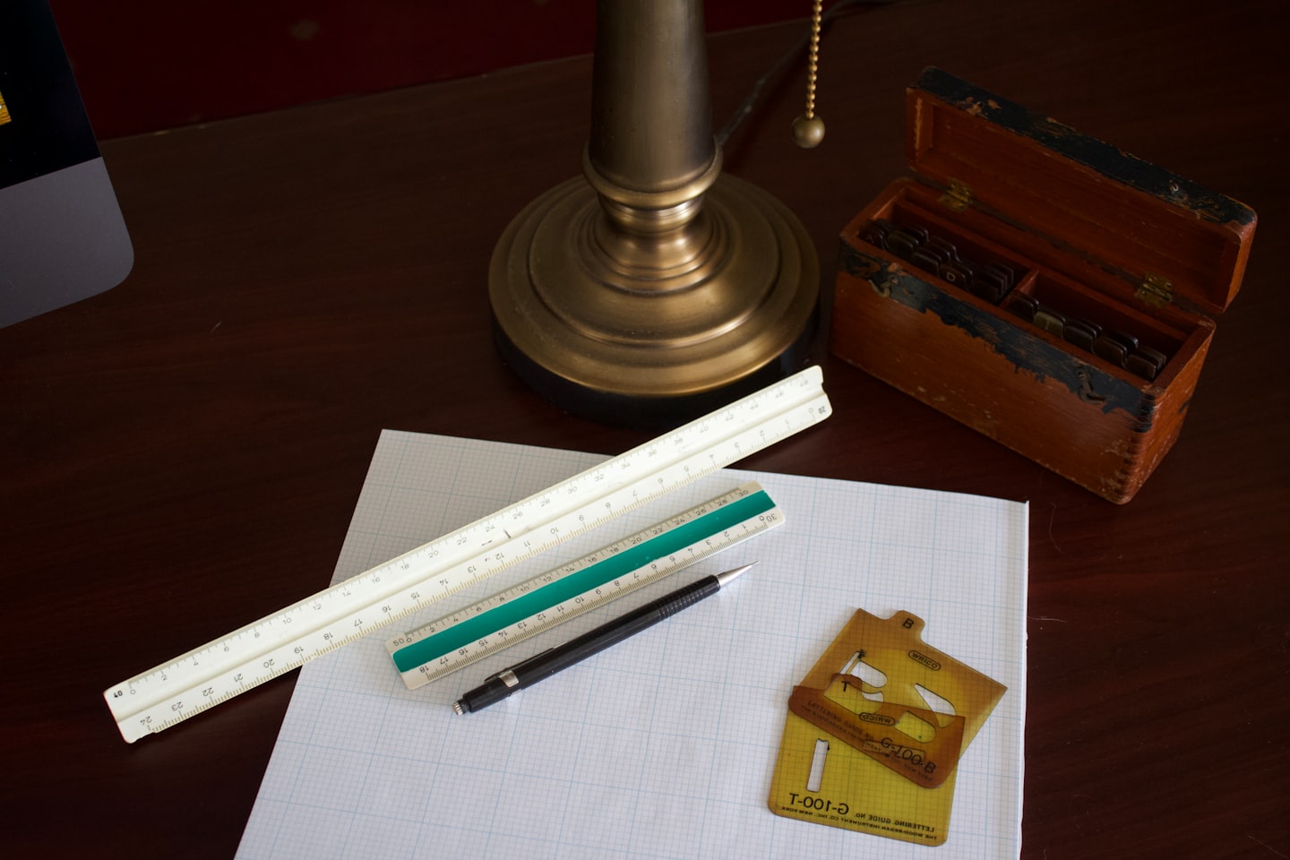 Strumenti da disegno e carta millimetrata su una scrivania di legno scuro.