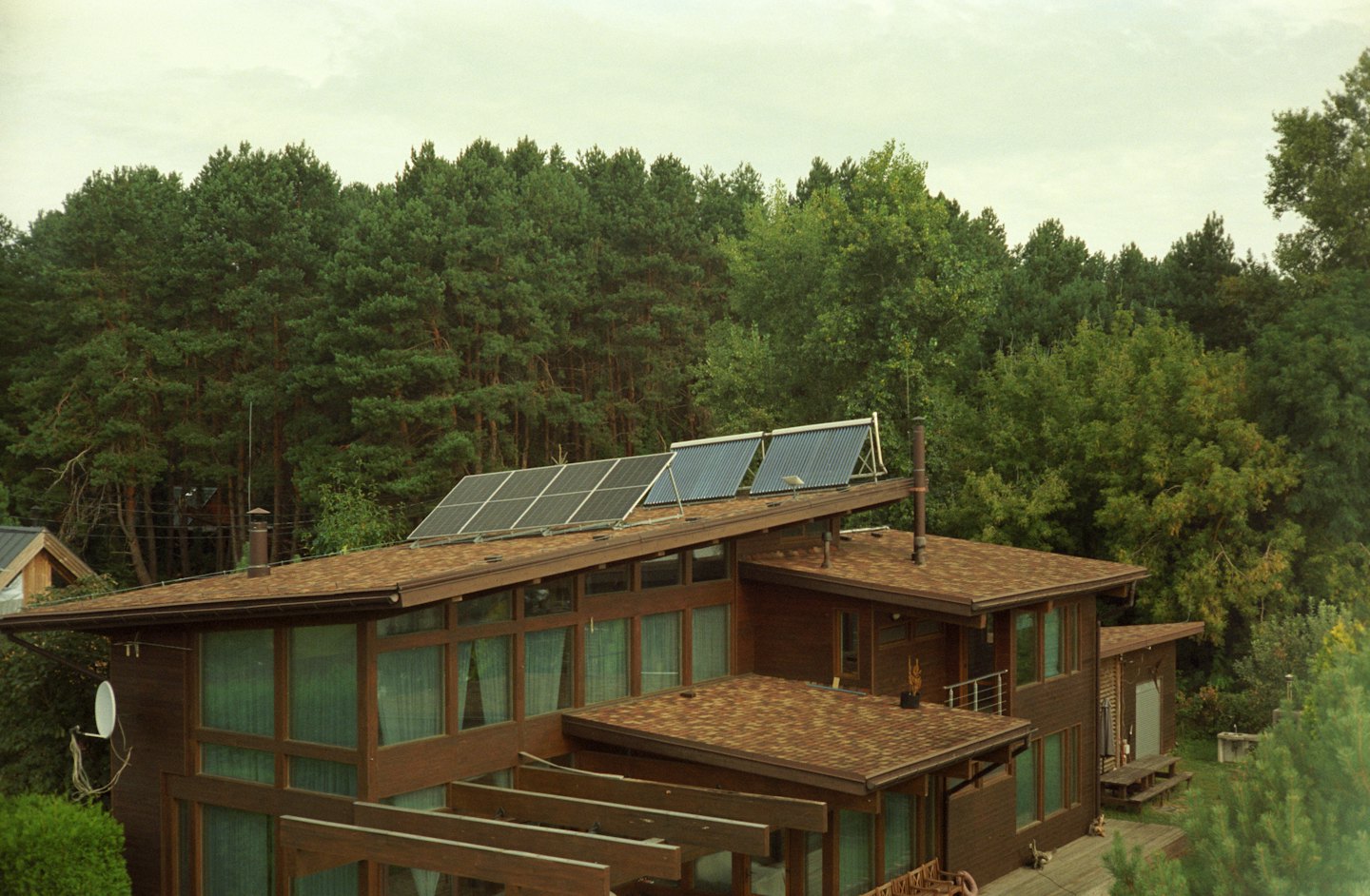Moderna casa in legno con pannelli solari su un tetto con sfondo forestale.
